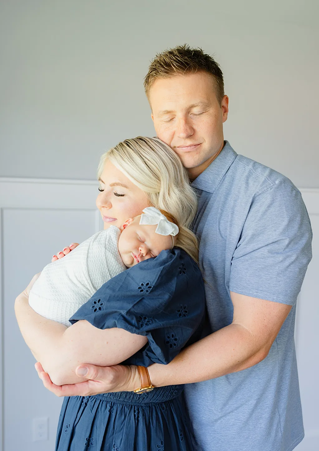 Mom and dad snuggle their baby girl in at home newborn photos. 
